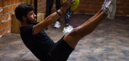 Focused man performing core exercises with a medicine ball in an indoor gym highlighting fitness and strength.
